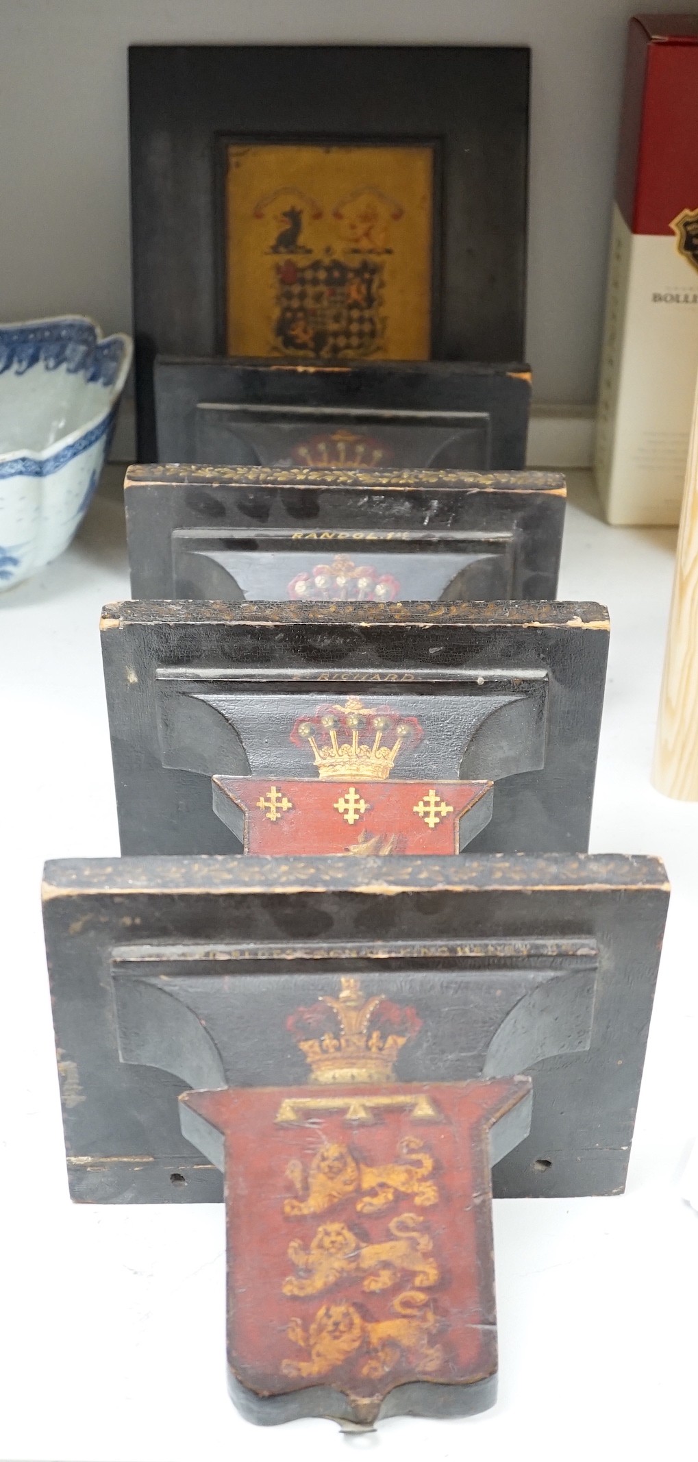Four 19th century painted and ebonised heraldic wall brackets together with a 19th century armorial plaque